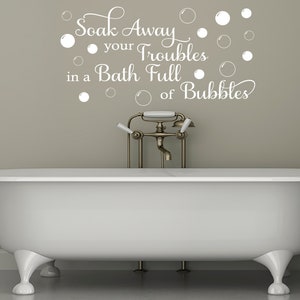 May include: White bathtub with a gold faucet and a wall decal that reads "Soak Away your Troubles in a Bath Full of Bubbles" with white bubbles surrounding the text.