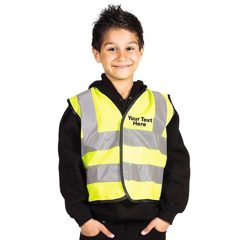 Peut inclure: Un gilet de s&eacute;curit&eacute; jaune avec des bandes r&eacute;fl&eacute;chissantes argent&eacute;es. Le gilet a une &eacute;tiquette noire qui dit "Your Text Here".