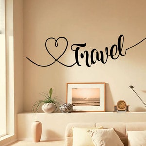 May include: A black and white wall decal with the word "Travel" written in a cursive font. A heart shape is drawn with a line connecting to the word "Travel". A small airplane is drawn at the end of the line.