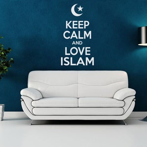 May include: A white sofa with a white wall behind it. The wall has a white crescent moon and star design with the text "Keep Calm and Love Islam". A black lamp is on the right side of the sofa.