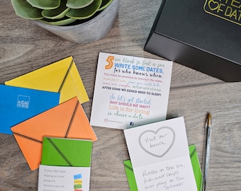 May include: A set of colorful envelopes with a green envelope on top. The envelopes have a variety of text on them, including "Write Some Dates" and "Visit our beach".
