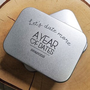 May include: A silver metal tin with the text "Let's date more A YEAR OF DATES seasons" printed on it.