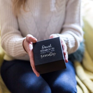 May include: A black gift box with the text "David things to do when you are seventy" printed in white.