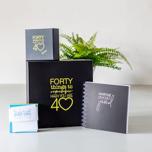 May include: A black gift box set featuring the text FORTY things to remember WHEN YOU ARE 40 with a heart icon, a smaller matching box labelled FORTY things to do WHEN YOU ARE 40 Brian, a spiral-bound making memories journal, and a small note pad.