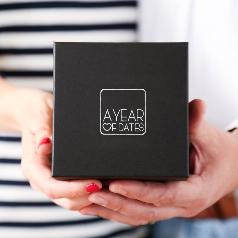 May include: A black box with a white logo that says "A Year of Dates" with a heart symbol.