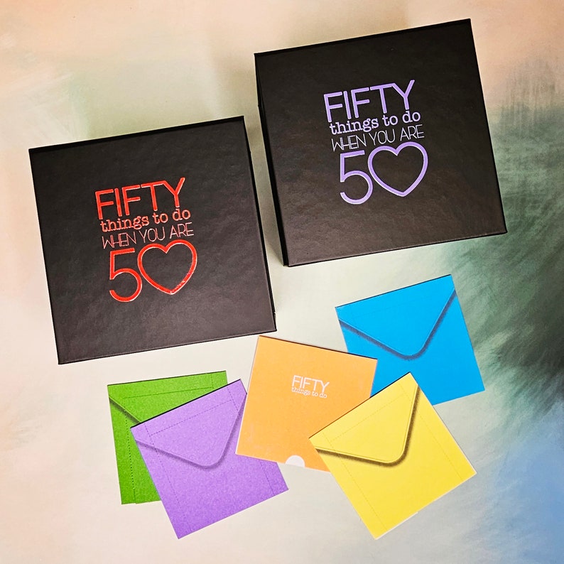 K&ouml;nnte beinhalten: Zwei schwarze Boxen mit dem Text "FIFTY things to do WHEN YOU ARE 50" in Rot und Lila. Die Boxen sind von f&uuml;nf bunten Umschl&auml;gen mit dem Text "FIFTY things to do" in Wei&szlig; umgeben.
