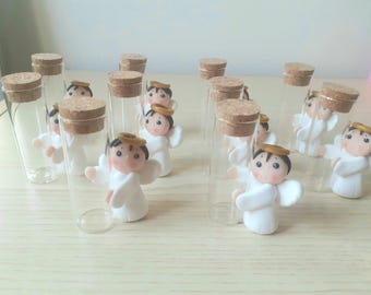 Könnte beinhalten: Eine Sammlung kleiner Glasflaschen mit Korkverschlüssen, jede mit einer Miniatur-Engelfigur aus weißem Porzellan mit goldenem Heiligenschein. Die Engel haben schwarze Haare und sind in einer Reihe auf einer hellbraunen Holzoberfläche angeordnet.