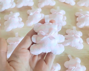 May include: A collection of pink plush teddy bears with satin bows. The bears are arranged in a random pattern on a light brown surface.