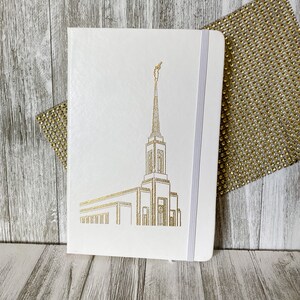 May include: White journal with a gold foil design of a temple on the front cover. The journal has a white ribbon bookmark.