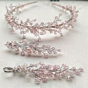 May include: A set of delicate pink beaded hair accessories. The set includes a headband and two long, dangling earrings. The beads are small and iridescent, giving the jewelry a soft, romantic look.
