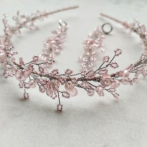 May include: A delicate pink beaded headband with a floral design. The headband is made of wire and features small pink beads and crystals.