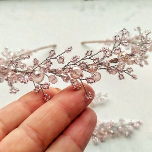 May include: A delicate pink beaded headband with a floral design. The headband is made of wire and features small pink beads and crystals.