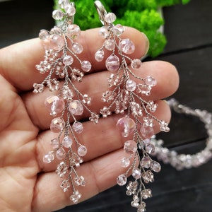 May include: A pair of long, delicate earrings with pink crystal beads and silver wire. The earrings are dangling and have a cascading effect.