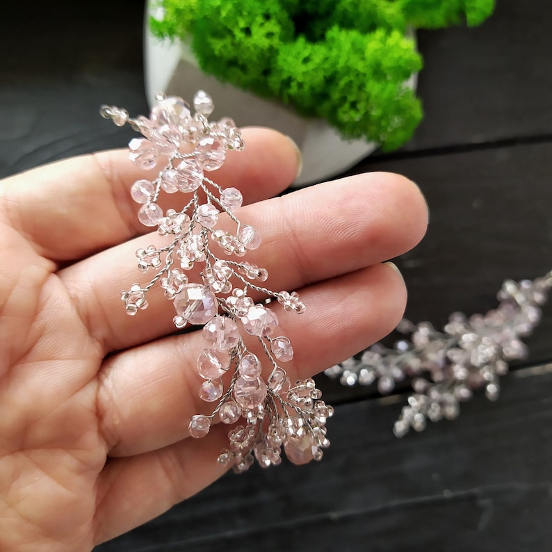 May include: A delicate pink crystal hair vine with a cascading design. The vine is made of small, faceted crystals and is perfect for adding a touch of sparkle to any hairstyle.