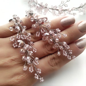 May include: A pair of delicate pink crystal earrings with a cascading design. The earrings are made with small, faceted crystals that are strung on wire branches.