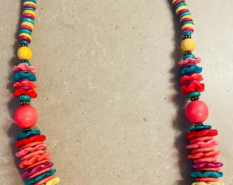 May include: A colorful necklace featuring a variety of beads in shades of turquoise, yellow, pink, red, and purple. The necklace has a mix of round and disc-shaped beads, creating a vibrant and eye-catching accessory.