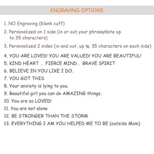 K&ouml;nnte beinhalten: Eine Liste von Gravur-Optionen f&uuml;r ein Armband oder anderen Schmuck. Die Optionen umfassen "Keine Gravur", "Personalisiert auf 1 Seite", "Personalisiert auf 2 Seiten", "YOU ARE LOVED! YOU ARE VALUED! YOU ARE BEAUTIFUL!", "KIND HEART. FIERCE MIND. BRAVE SPIRIT", "BELIEVE IN YOU LIKE I DO.", "YOU GOT THIS", "Your anxiety is lying to you.", "Beautiful girl you can do AMAZING things.", "You are so LOVED!", "You are not alone", "BE STRONGER THAN THE STORM", und "EVERYTHING I AM YOU HELPED ME TO BE (outside Mom)".