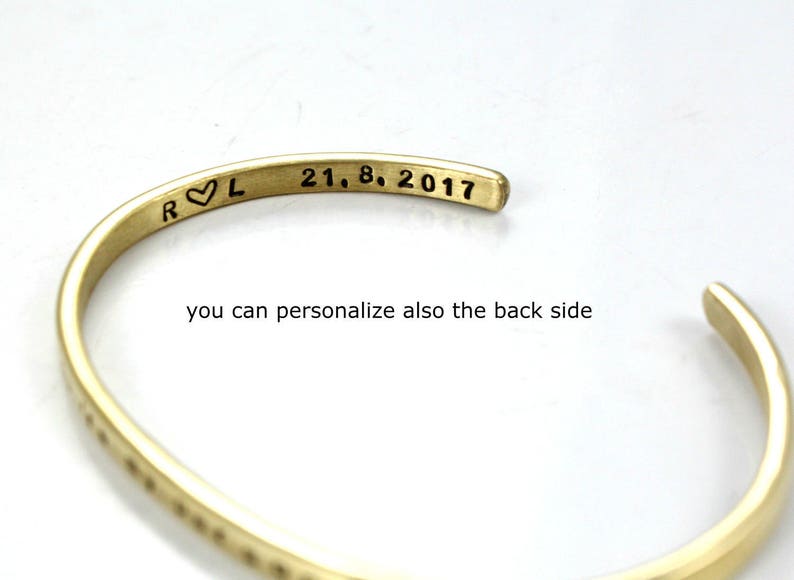 May include: A gold-toned metal bracelet with an inscription that reads "R &hearts; L 21. 8. 2017".