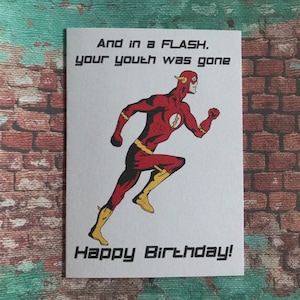 Può includere: Biglietto di auguri bianco con il supereroe Flash in posa di corsa. Flash indossa un costume rosso e giallo. Il biglietto riporta la scritta "And in a FLASH, your youth was gone" e "Happy Birthday!"