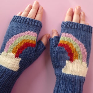 May include: A pair of blue fingerless gloves with a rainbow design. The rainbow is made of pink, green, orange, red, and yellow yarn. The gloves have a white cloud design at the bottom.