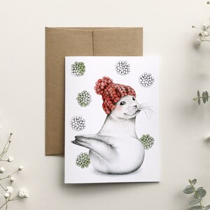 Carte de souhait phoque aux pompons, illustration animal marin tricot laine, carte de voeux fêtes, dessin aquarelle noël, Katrinn Pelletier