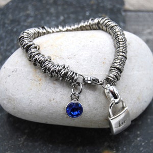 May include: A silver bracelet with a blue crystal charm and a padlock charm that says "love".