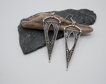 May include: A pair of silver triangle earrings with intricate cutouts and a beaded detail at the bottom.
