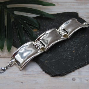Pulsera envolvente plateada con diseño curvo y grueso