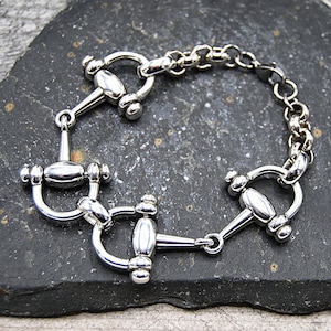 May include: A silver bracelet with three silver horse bit charms and a silver chain.