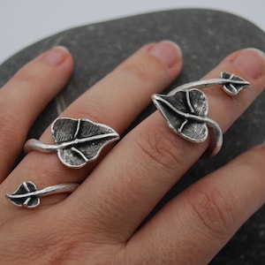 May include: Two silver rings with leaf designs. The rings are adjustable and can be worn on different fingers.