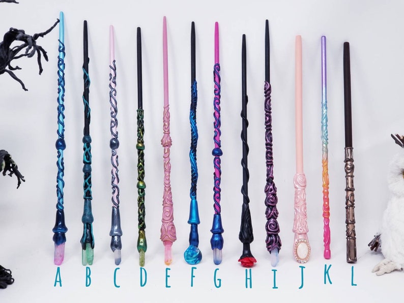 May include: A selection of twelve handcrafted wands, each with unique designs and colours. The wands feature intricate details, including swirling patterns, crystal tips, and various colour schemes such as blue, pink, and black. Each wand is approximately 30 cm long.