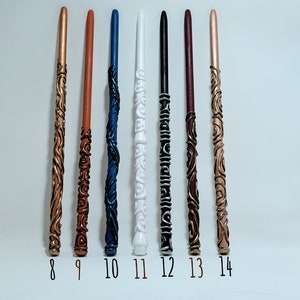 May include: Seven handcrafted wands in various colours, including copper, brown, blue, white, black, burgundy, and rose gold. Each wand features unique decorative designs and is numbered from 8 to 14.