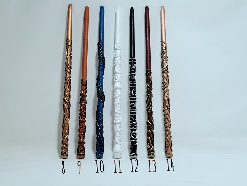 May include: Seven handcrafted wands in various colours, including copper, brown, blue, white, black, burgundy, and rose gold. Each wand features unique decorative designs and is numbered from 8 to 14.