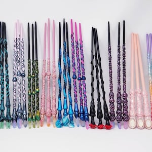 May include: A selection of decorative wands in shades of blue, pink, black, and purple. Each wand has detailed patterns, crystal-like tips, and ornate handles. The wands are displayed in a row, highlighting their individual designs and styles.