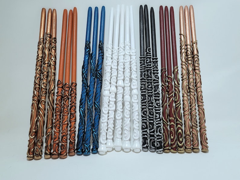 May include: A selection of decorative wands in various colours, including copper, orange, blue, white, black, and burgundy. Each wand features intricate, swirling designs and is approximately 30 cm long.