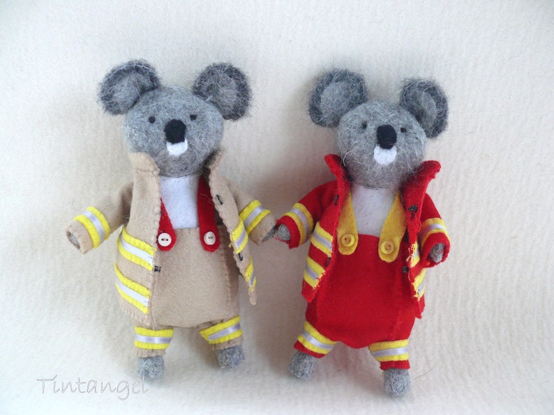 In this picture: two handmade felt koala bears, both dressed as a firefighter, one in a red costume, the other in a sand-colored costume. all clothing has refelcting stripes in yellow and silver.  All is made with a PDF handsewing pattern from WoolFeltWonders, part of a series with toy animal and clothing patterns to mix and match, to portray hobby or profession for play.