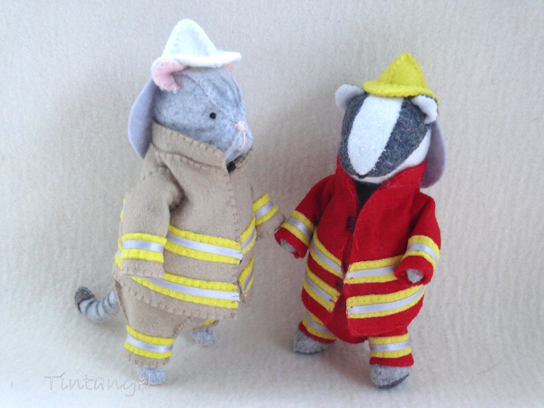 In this picture: two handmade felt toy animals, cat and badger, both dressed as a firefighter, one in a red costume, the other in a sand-colored costume. All clothing has refelcting stripes in yellow and silver. The badger with the red costume wears a yellow helmet, the other has a white helmet. All is made with a PDF handsewing pattern from WoolFeltWonders, part of a series with toy animal and clothing patterns to mix and match, to portray hobby or profession for play.
