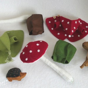 May include: A set of felt toys including a mushroom, a deer, a hedgehog, and a few other felt shapes. The toys are all handmade and have a whimsical, woodland theme.