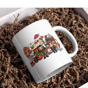 Può includere: Tazza in ceramica bianca con un design natalizio con personaggi della serie Harry Potter. I personaggi sono raffigurati in un'ambientazione festosa con un albero di Natale, regali e uno sfondo innevato.