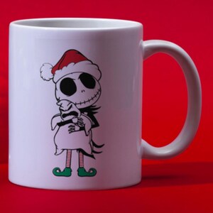 Puede incluir: Taza de cer&aacute;mica blanca con una ilustraci&oacute;n en blanco y negro de Jack Skellington de Pesadilla Antes de Navidad con un gorro de Pap&aacute; Noel y sosteniendo un saco.