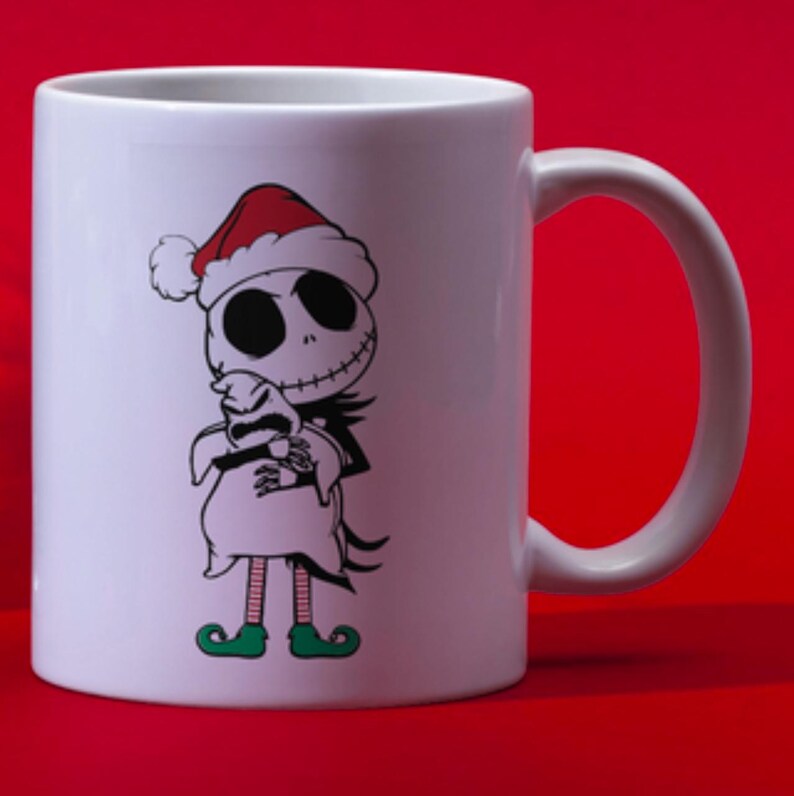 Puede incluir: Taza de cer&aacute;mica blanca con una ilustraci&oacute;n en blanco y negro de Jack Skellington de Pesadilla Antes de Navidad con un gorro de Pap&aacute; Noel y sosteniendo un saco.