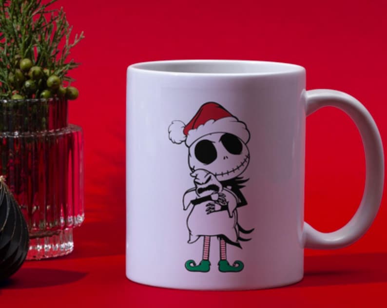 Puede incluir: Taza de cer&aacute;mica blanca con un dise&ntilde;o navide&ntilde;o con Jack Skellington de Pesadilla antes de Navidad con un gorro de Pap&aacute; Noel y sosteniendo un fantasma blanco. La taza tiene un asa negra.