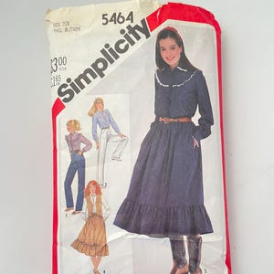 Puede incluir: Un sobre de patrón de costura Simplicity 5464 para talla joven junior/adolescente 7/8. El frente muestra ilustraciones de varios atuendos, incluyendo un vestido azul oscuro de manga larga con cuello de volantes blanco y cinturón marrón.