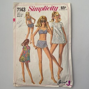 Peut inclure: Une enveloppe de patron de couture Simplicity vintage avec des illustrations de maillots de bain et de robes pour adolescentes. L'enveloppe est usée et déchirée, et comprend le texte "Simplicity" et "65c". Le patron est pour la taille 10T avec un tour de poitrine de 30.