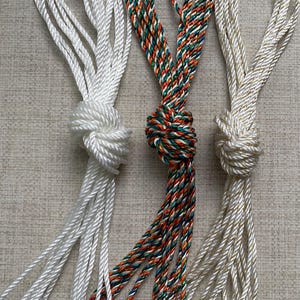 May include: Three spools of cord, one white, one gold, and one with a multi-coloured pattern of green, orange, and red.