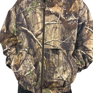 Puede incluir: Una chaqueta de camuflaje con cierre de cremallera y cordón en la parte inferior. La chaqueta está hecha de un material suave y cómodo y tiene un corte holgado.