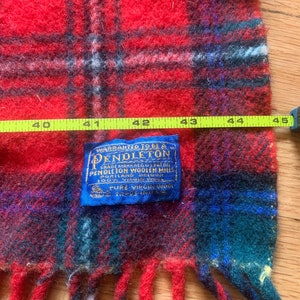 Op de afbeelding: Rode en groene geruite Pendleton wollen sjaal met franjes. Het label luidt "Warranted to be a Pendleton Trade Mark Registered U.S. Pat. Off. Pendleton Woolen Mills Portland, Oregon 100% Virgin Wool Pure Virgin Wool Made in U.S.A."
