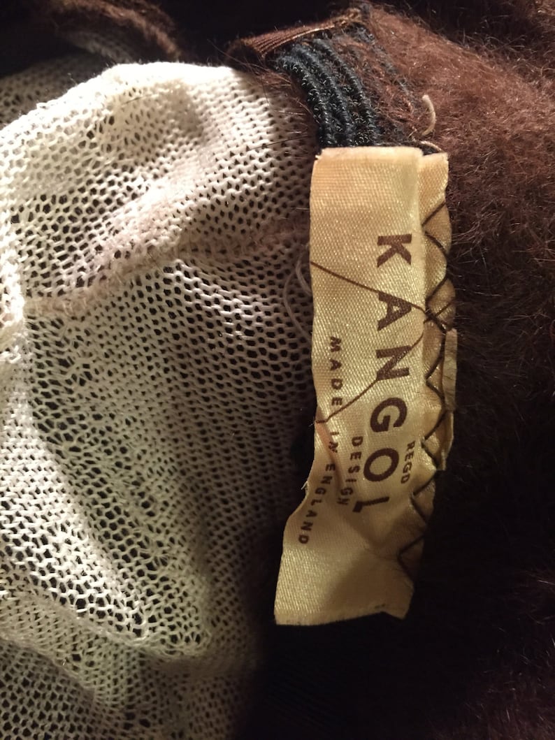 May include: A brown fur coat with a white mesh lining and a brown leather label that reads "Kangol Rego Design Made in England".