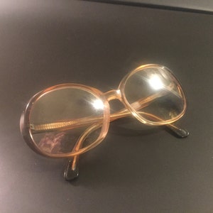 May include: A pair of round, brown-tinted eyeglasses with a gold metal frame.