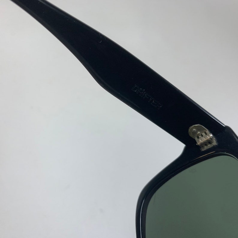 Peut inclure: Lunettes de soleil noires avec des verres verts et le mot "Drifter" imprim&eacute; sur le c&ocirc;t&eacute;.